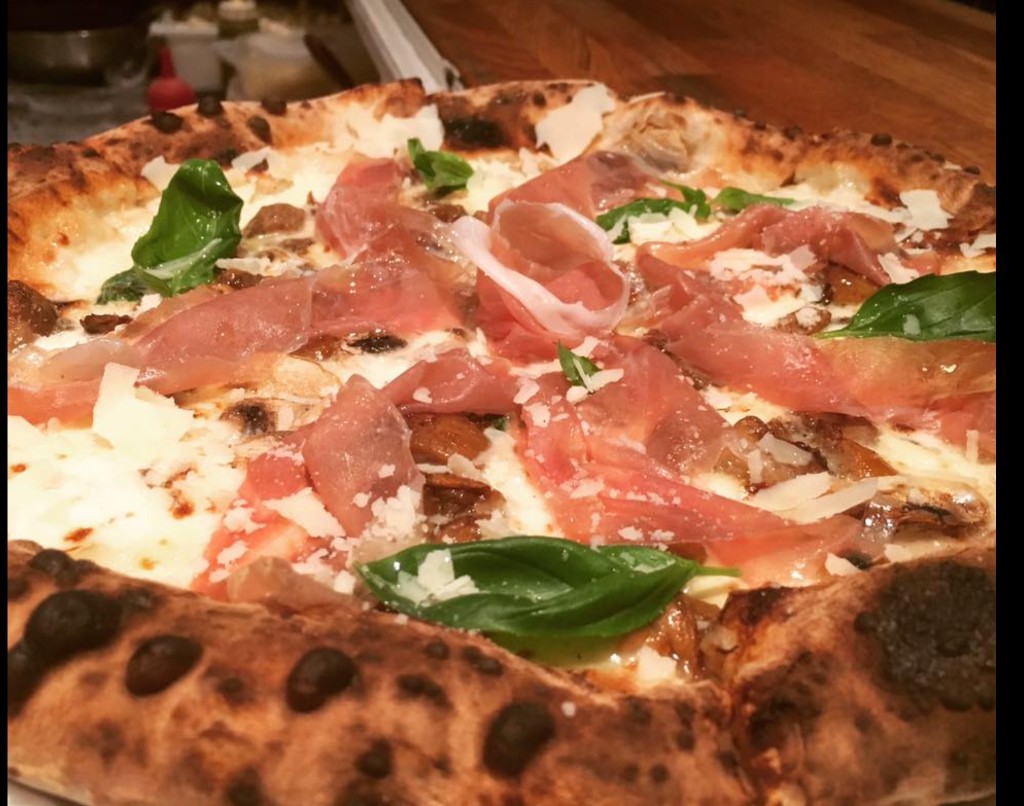 Rustica white pizza with mushrooms, speck, basil and truffle oil on a charred crust